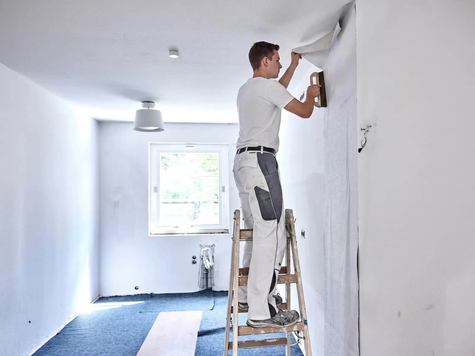 Maler bei Tapezierarbeiten an der Wand